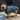 Dog wearing a blue puffer coat standing on a wooden floor